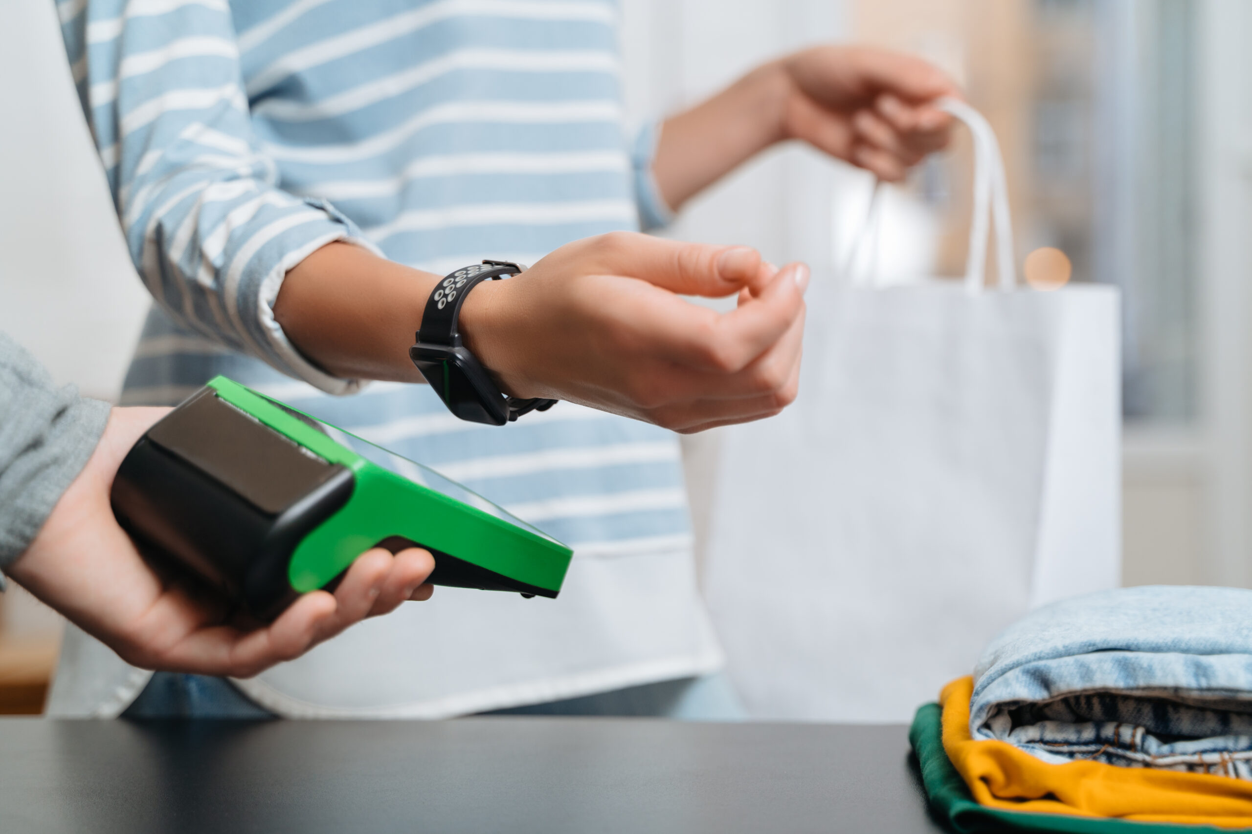 Closeup of woman paying for purchase by smart watch with nfc tec